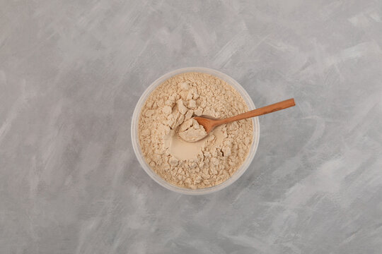 Soy Protein isolate in plastic container, top view. Pure powder  isolated from soybean. Soy protein isolate is often used in meat industry in production of minced meat and sausages