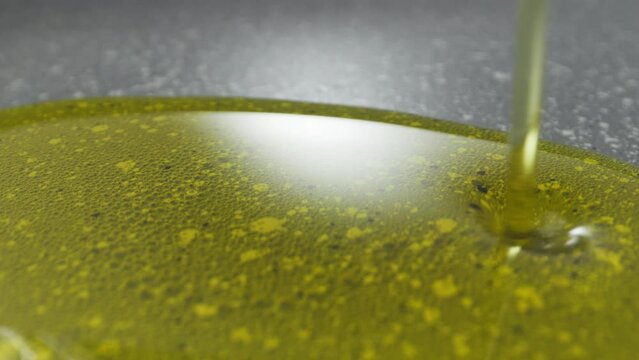 olive oil is poured into a gray frying pan. shooting at close range. High quality 4k footage