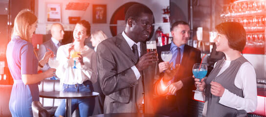 Respectable African man enjoying conversation with female colleague on corporate party in bar