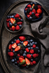 Fresh summer wild berries on a black plates. Dark background. Top view.