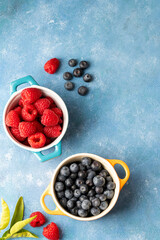 Fresh berries. Blueberry and raspberry in ceramic bowls. Colourful fruit, food background, top view.