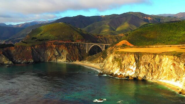 Panning Shot Of Bixby Creek Bridge By Sea And Mountains Under Cloudy Sky - San Francisco, California