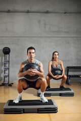 Sporty man and woman doing squats with fitness medicine slam ball in the gym.