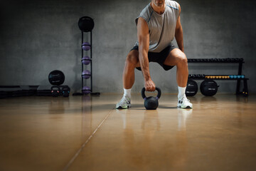 Athletic man lifting weight with kettle bell or dumbbell