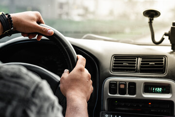 close-up of a latin man's hands, holding the steering wheel, while driving with a beautiful sunset...