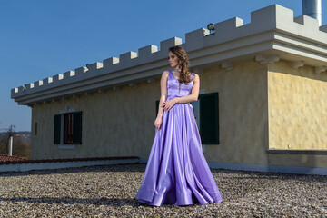 Young woman in a purple dress is standing on the roof of a building