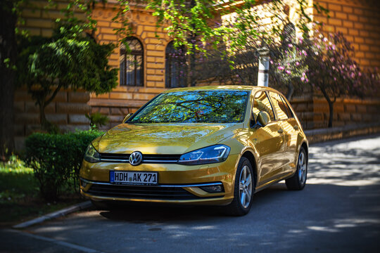 Beautiful golden color Volkswagen Golf 7 is parked in square of Patriarchal Palace. Shot made with vintage-style swirly bokeh Lens Baby "Twist 60" - 13.04.2022 Sremski Karlovci, Serbia
