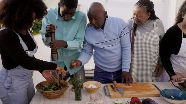 Outdoor kitchen: Happy African family cooking vegan food together at home terrace