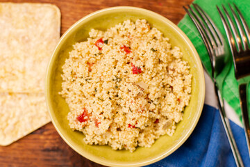 couscous, spices and tomato tabbouleh salad with rice bread in a yellow plate on a wooden background. Traditional oriental salad, appetizer.