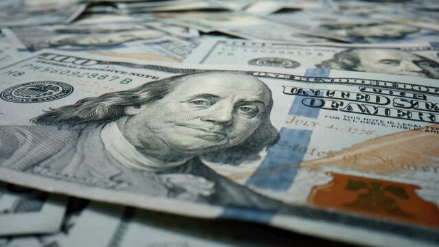 Closeup hundred dollar banknote lying on large heap american currency rotating. 