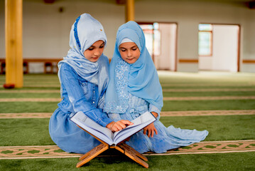 Two Muslim girls reading a holy book Quran inside the mosque. 