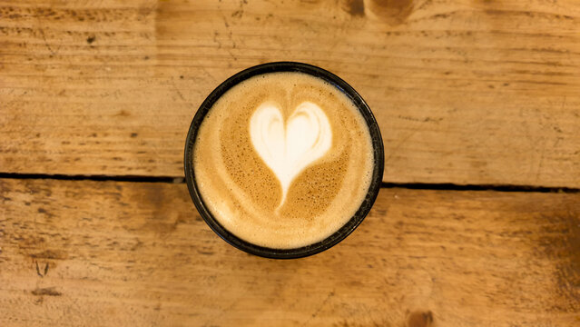 Golden Flat White Coffee With Heart Shaped Coffee Art On Rustic Wooden Table, Top Down View