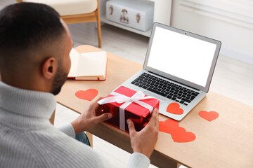 Valentine's day celebration in long distance relationship. Man holding gift box while having video...