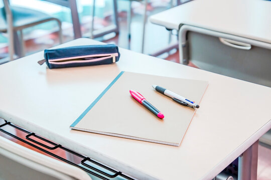 教室の机の上に置かれたノートとペン、ペンケース。学校生活のイメージ、背景素材