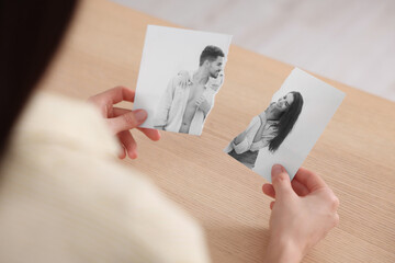 Divorce and breakup. Woman holding parts of ripped black and white photo at table, closeup