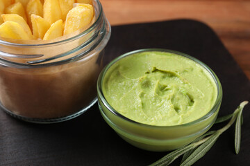 Serving board with french fries, guacamole dip and rosemary on wooden table, closeup
