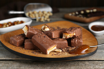 Tasty chocolate bars with caramel and nuts on wooden table, closeup