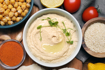Delicious hummus with microgreens and different ingredients on wooden table, flat lay