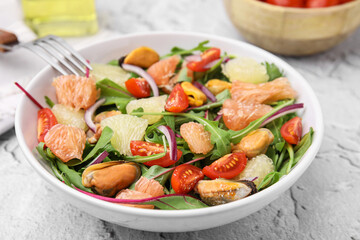 Delicious pomelo salad with tomatoes and mussels on white textured table, closeup
