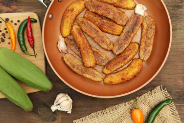 Delicious fried bananas, fresh fruits and different peppers on wooden table, flat lay