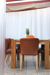 Wooden table with fruits and stylish chairs on terrace