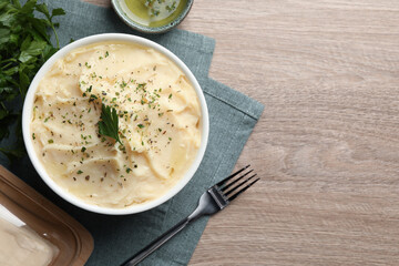 Delicious mashed potato with parsley served on wooden table, flat lay. Space for text