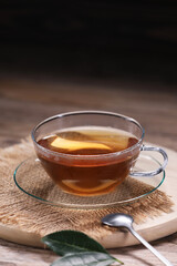 Aromatic hot tea in glass cup and leaves on wooden table