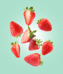 Delicious sweet strawberries falling on pale turquoise background
