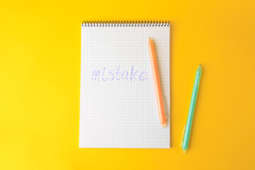Word Mistake written in notepad with erasable pen on yellow background, flat lay
