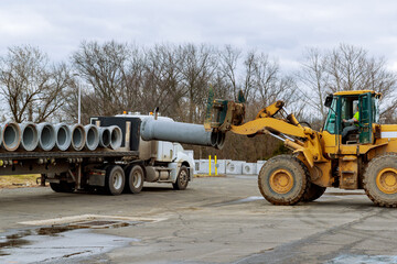 Obraz premium stacked concrete pipes and loaded flatbed trailer delivery