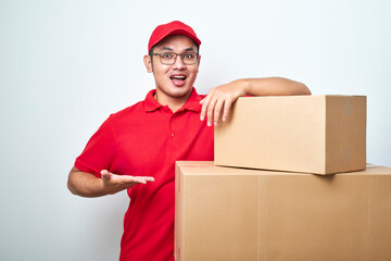 Confident asian courier man in red uniform encourage call service, showing and pointing at...