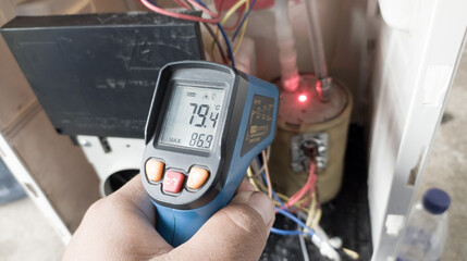electrician is using a thermogun to analyze water heater and components of dispenser.