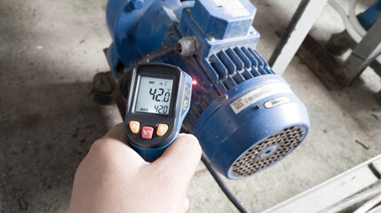 An engineer checking the temperature on an electric motor using an infrared temperature gun.