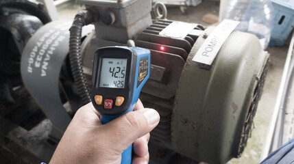 An engineer checking the temperature on an electric motor using an infrared temperature gun.