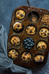 A rustic muffin tin filled with homemade blueberry muffins fresh out of the oven