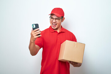 Asian courier man in red uniform smiling look at his smartphone while holding cardboard box parcel