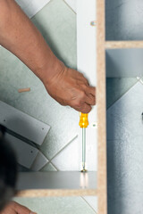 A man using a screwdriver to assemble a closet