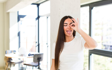 Obraz premium young adult pretty woman smiling happily with funny face, joking and looking through peephole, spying on secrets