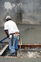 Mason using a bull float on freshly poured concrete