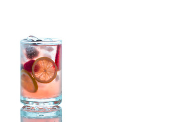 A glass on cool cocktails with a garnish of lemon slices,berry  and ice cubes isolated on white background for effect.