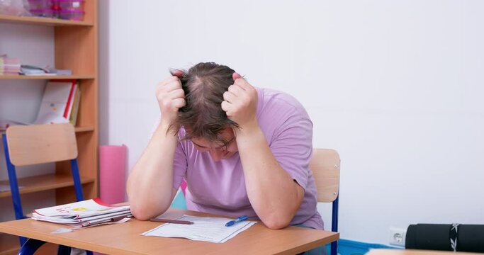 Man sits at desk in classroom, tears his hair out in panic, cannot concentrate test learning difficulties poor memory study impairment age self-doubt . Training lifelong learning. exam stress anxiety