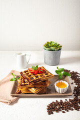 Belgian waffles with fresh berries and mint on a white background