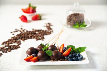 Chocolate candies with strawberries and blueberries on a white background
