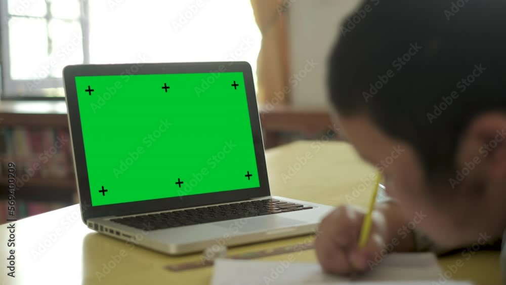 Aufkleber chroma key green screen modern laptop computer set up for work on desk with boy doing homework backg