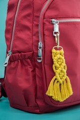 Close-up view of the handmade Macrame key chain hanging on the red backpack isolated on the tiffany...