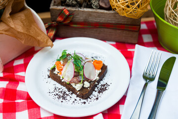 Sandwiches with cream cheese, vegetables and salted herring on a white plate