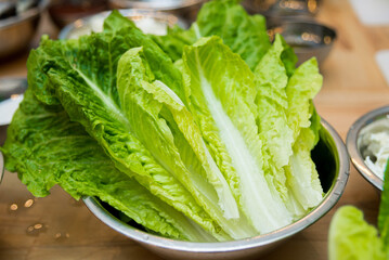 Lettuce in a bowl on a wooden table. Uncooked fresh leaves. Before cooking salad.