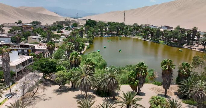 Desert oasis Huacachina, Peru with lake and palms, with great sand dunes in the background. Lost in the wilderness, hidden natural gem for holiday adventure. Aerial above view drone high resolution 4k