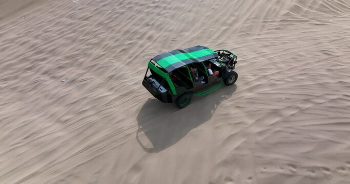 Dune buggies in Huacachina, Peru desert. Fast sand buggy driving on the sand dunes in the desert. Outdoor motorsports activities on a fun sunny day. Aerial above view drone high resolution 4k