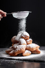 Stacked beignets with powdered sugar on black backround